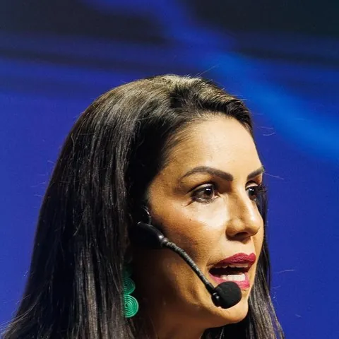 Letícia Silva, fonoaudióloga, segurando uma letra A de feltro e um card com o gesto da boca